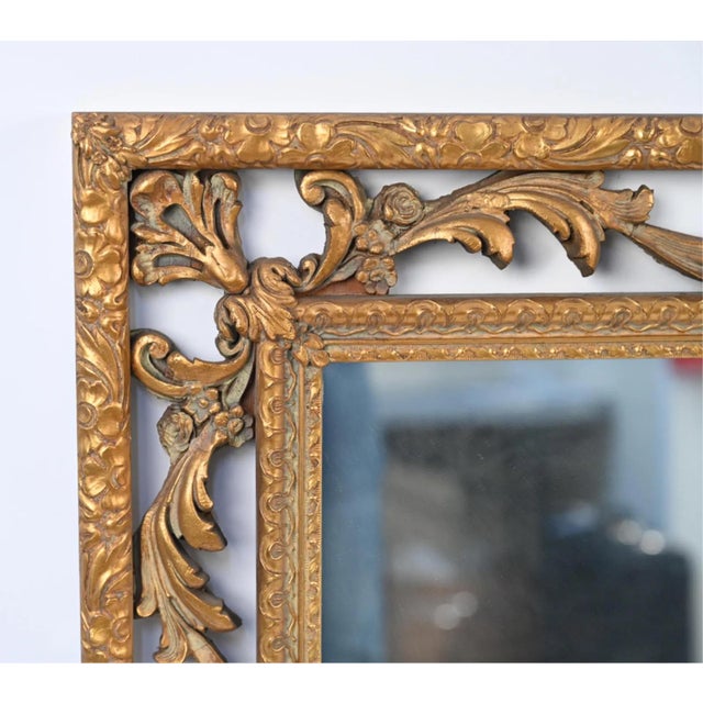 A large vintage rectangular gold tone Italian Baroque style wall mirror with a warm, slightly worn golden tone with traces...