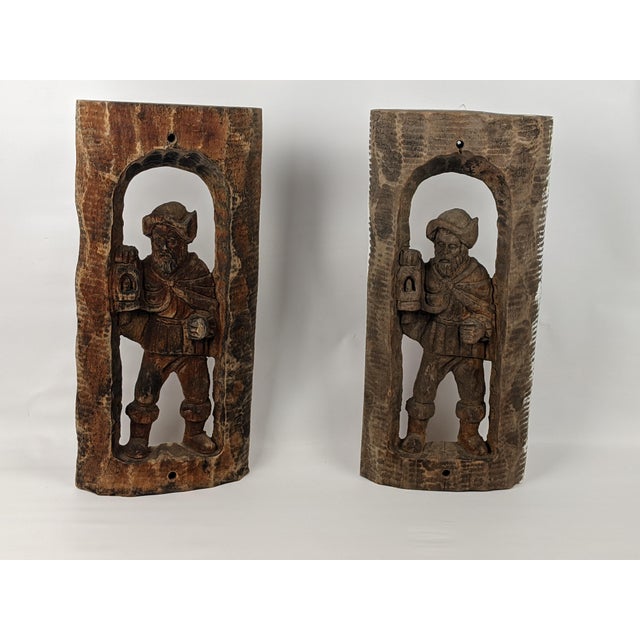 A distinctive pair of mid-20th-century hand-carved wood figural relief panels depicting traditional watchman or guard...