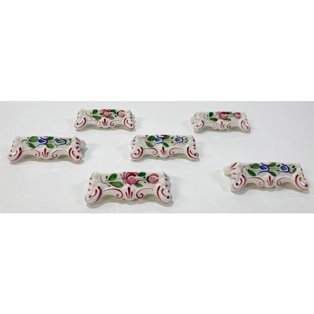 Set of six antique French hand made and hand-painted porcelain knife rests. Each depicts lovely floral design with deep...