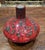 A vintage ceramic Fat Lava vase featuring its signature red and black cratered glaze, crafted in a unique UFO shape.