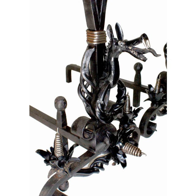 Pair of antique late 19th century hand-wrought andirons with ornate decorative metalwork. Andirons rest on scrolled bases...