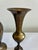 A sculptural pair of vintage brass bud vases featuring elegant trumpet tops and warm aged patina. The taller vase has a...