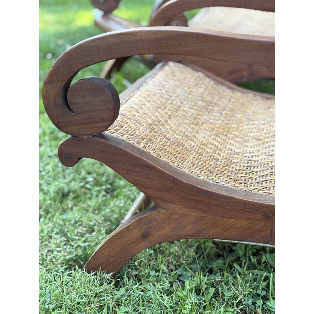 Handcrafted in Indonesia in the mid 20th century, this sculptural pair of teak and cane lounge chairs captures the relaxed...
