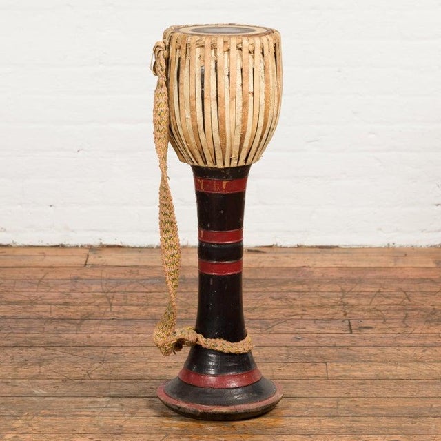 A Burmese tribal Ozi goblet shaped teak drum from the late 19th century, with red and black lacquer and calf skin top....