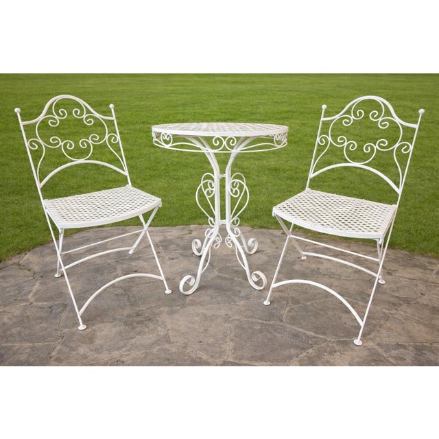 Elegant three-piece wrought iron bistro set consisting of a round café table and two folding side chairs, finely executed...