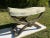 A single antique carved wood curule style stool or “x” bench with curved upholstered seat.