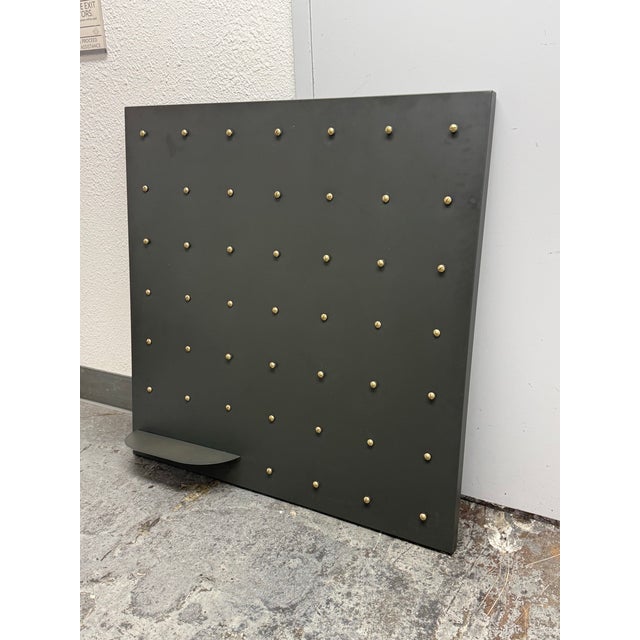 Design Plus Gallery presents a Display Panel with Studs and Shelf. The gray metal panel is a perfect square with a grid of...