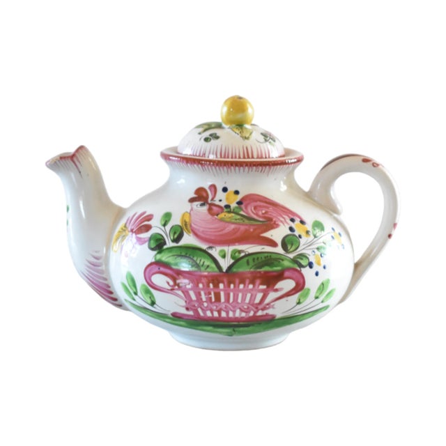 An antique, French faience teapot, hand-painted with a rooster and a basket of flowers, with an apple lid handle, and red...