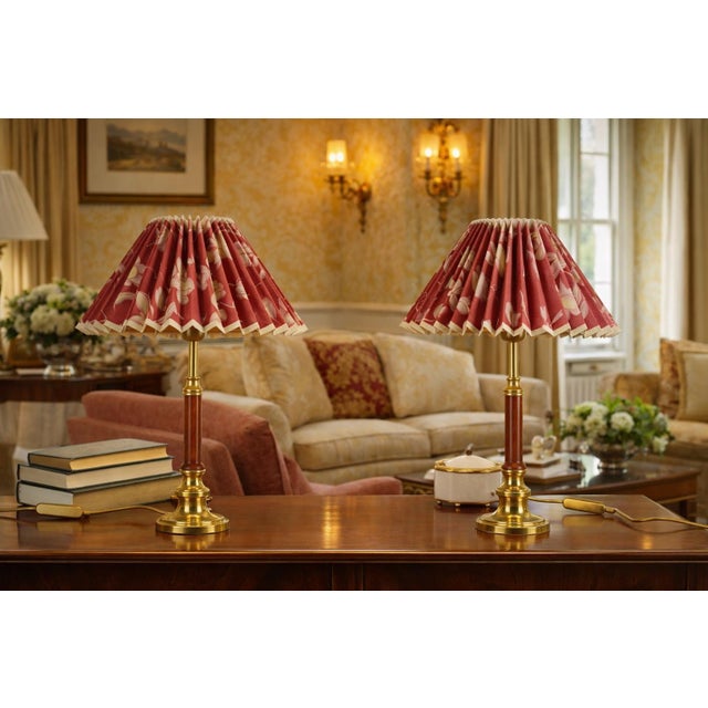 Matching pair of table lamps dating to the 1970s. Each lamp combines a warm wooden column with a stepped brass base and...
