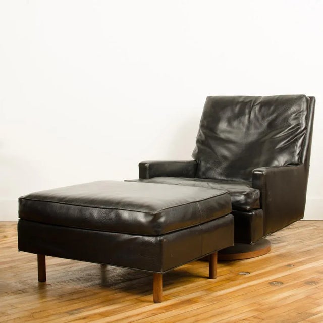 A Mid Century Modern black leather reclining lounge armchair with ottoman designed by Milo Baughman for James Inc,...