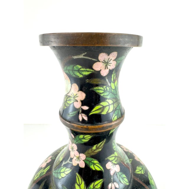 A richly detailed vintage cloisonné vase featuring a black enamel ground adorned with hand-applied cherry blossoms, leafy...