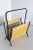 - Magazine rack in blackened wrought iron - With an insert in yellow-white striped plastic - Original condition