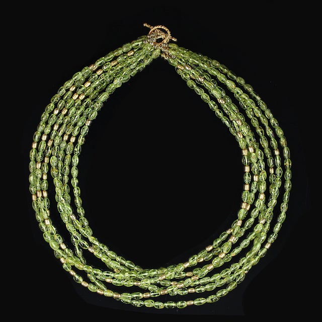 This handcrafted 18‑inch peridot necklace brings together seven shimmering strands of smooth peridot tubes, creating a...