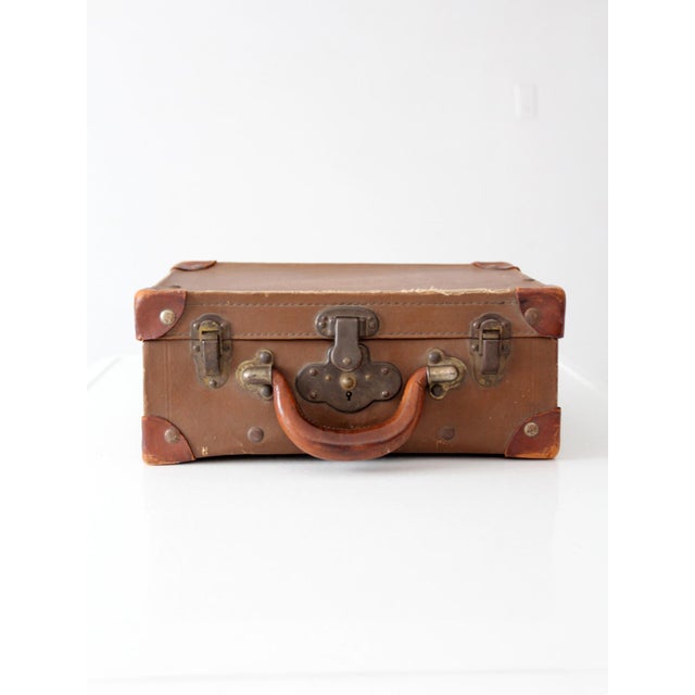 This vintage miniature leather suitcase brings the charm of early travel into the home. Wrapped in warm brown leather with...