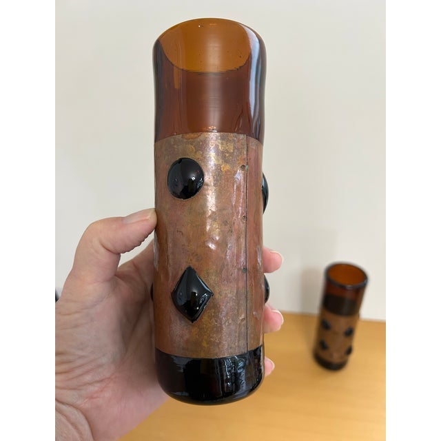 Set of 4 mid-century brutalist dark amber tumblers. They are hand-blown and wrapped in metal with internal cut-outs, also...