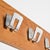 Wall-mounted coat rack composed of a plywood panel veneered in light mahogany, to which four aluminum hooks are attached....