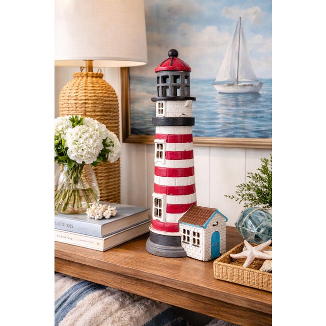 This substantial vintage cast iron lighthouse sculpture features a classic red and white striped design with a charming...