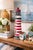This substantial vintage cast iron lighthouse sculpture features a classic red and white striped design with a charming...