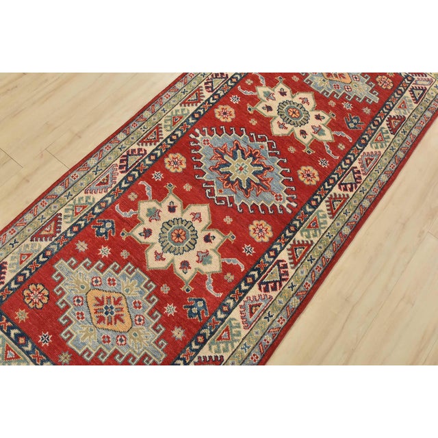 A tribal Caucasian Kazak runner hand-knotted with fine wool on a cotton foundation. This rug features a row of geometric...