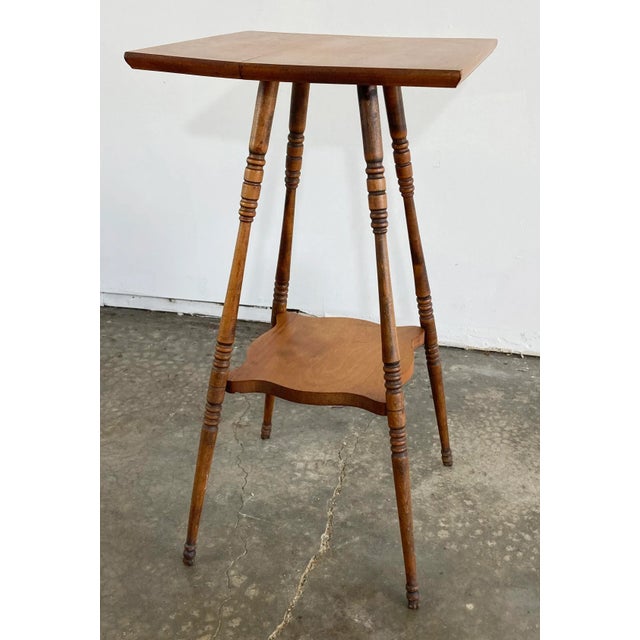 Handmade antique two tier side table with four petite turned splay wood legs attached by lower stretcher shelf. Square top...