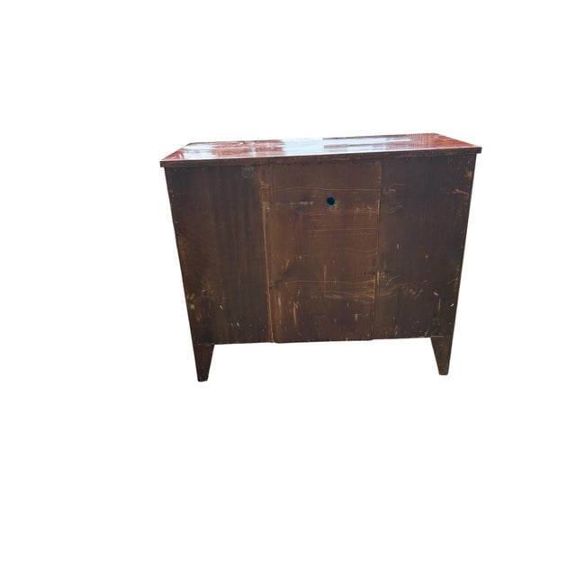 This piece is an antique flame mahogany chest of drawers featuring four graduated drawers accented with brass ring pulls...