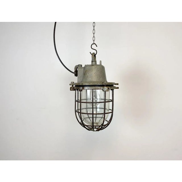 Industrial hanging lamp made in former Czechoslovakia during the 1960s. It features cast iron top, clear glass cover and...