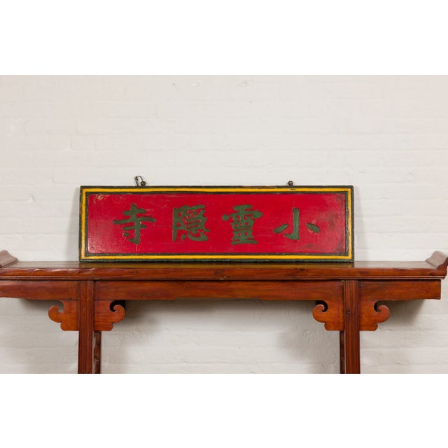 A Chinese late Qing Dynasty period red lacquered shop sign with hand carved calligraphy and black and yellow frame....