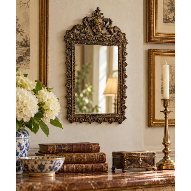 A wonderfully detailed antique French cast brass mirror dating to the early 20th century, featuring an elaborate heraldic...