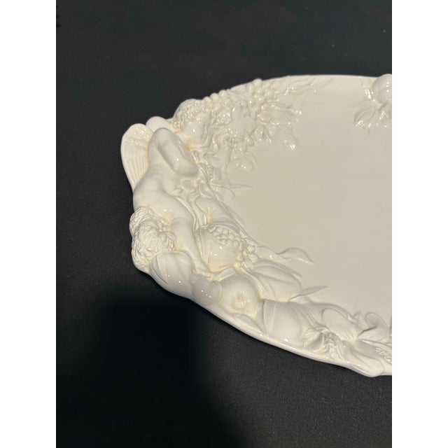 A wonderfully sculptural Italian ceramic platter featuring a charming cherub motif, beautifully blending European whimsy...