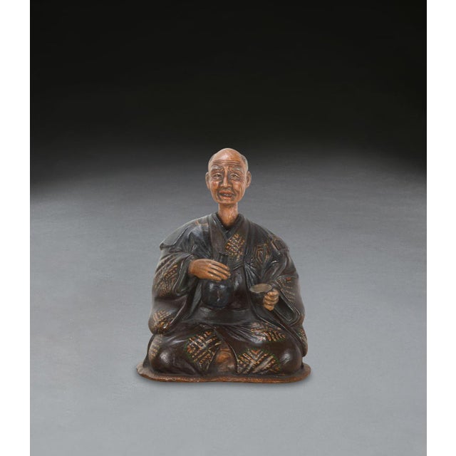 A rare c19th english pottery figure of a seated japanese gentleman in traditional robes, with a nodding head which is lead...