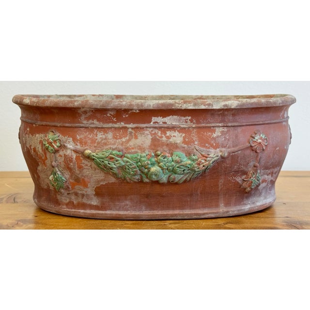 Weathered vintage oblong terra cotta planter with a green garland and medallion motif to both sides and ends. Heavy terra...