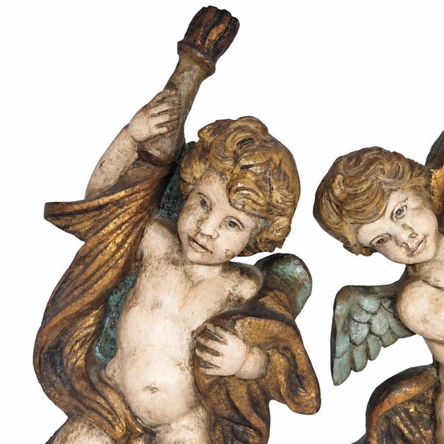 Pair of polychrome and gilded wooden torch-bearing putti - 19th century. Torch-bearing putti holding stylized torches; the...