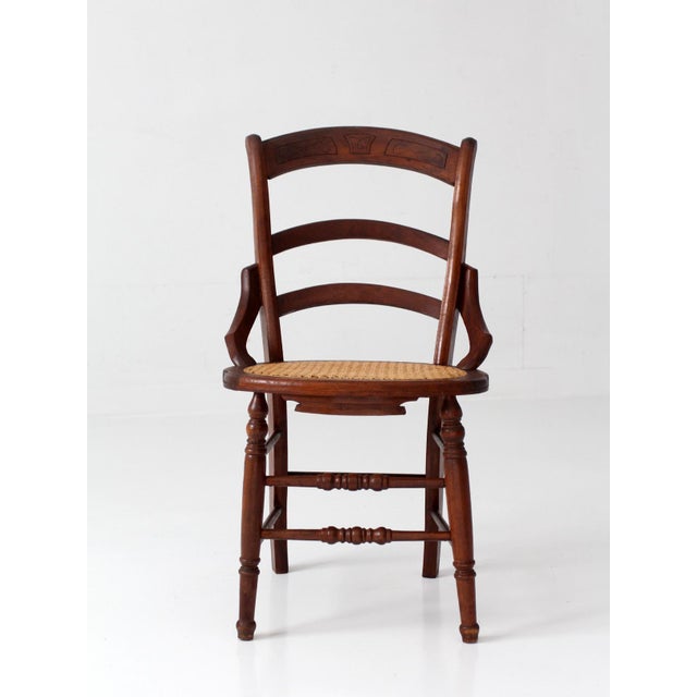 A late 19th century Eastlake style chair with a shaped ladder back, incised carved crest rail, and woven cane seat. The...