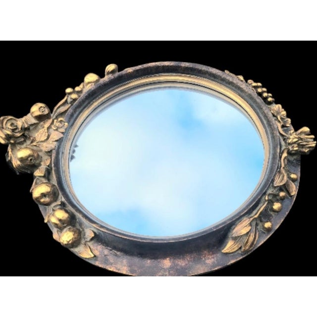 A wonderful round carved fruit and floral wall mirror. The mirror is made of a composite material with a pale black and...