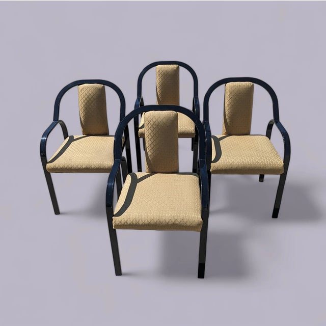 A set of four 1980s postmodern dining chairs with sculptural black lacquered metal frames and gold-tone patterned...