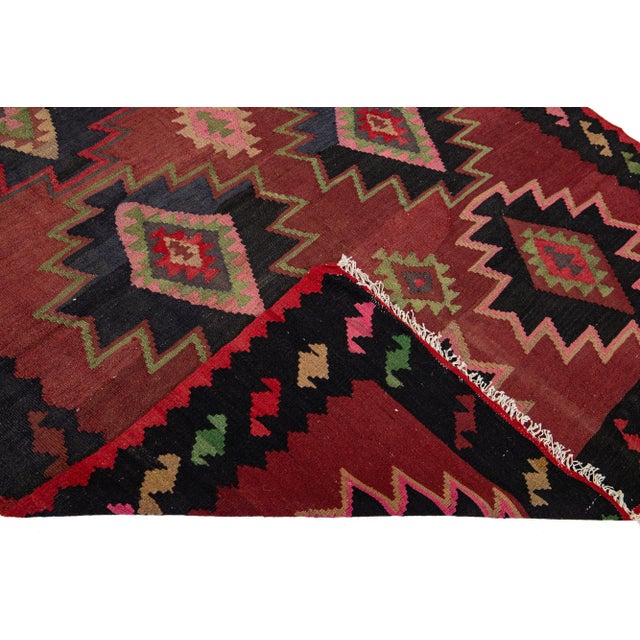 Beautiful vintage Turkish Kilim hand-knotted wool rug with a red field. This piece has a black frame and multicolor...