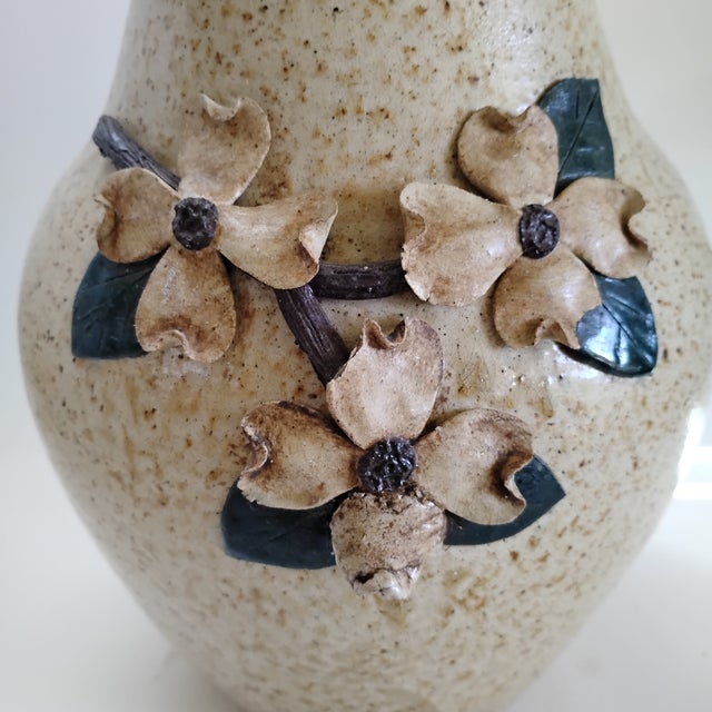 This handcrafted stoneware pitcher featuring applied dogwood blossoms and leaves is an authentic piece of Southern folk...