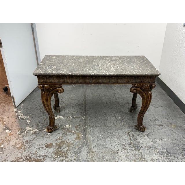 Design Plus Gallery presents an Antique Carved Wood Marble-Top Center Table. The rectangular marble slab displays a...
