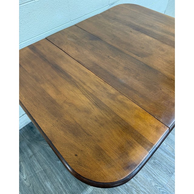 This is a handsome antique 1920s Colonial Revival gateleg drop leaf dining table crafted from solid maple. It features...