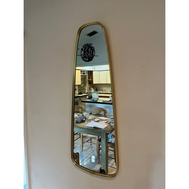 Bring sculptural Mid-Century style to any space with this striking vintage wall mirror featuring a slender organic...