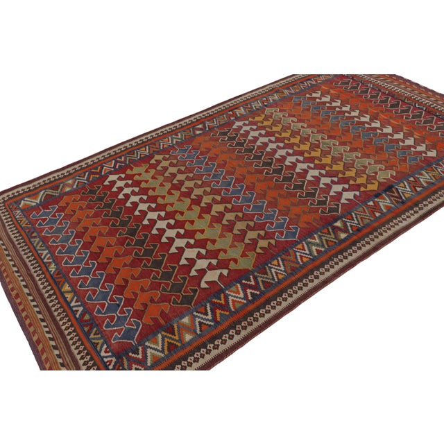 Handwoven in wool, circa 1950-1960, this 5x9 Afghani tribal Kilim rug, featuring vibrant colors and geometric patterns...
