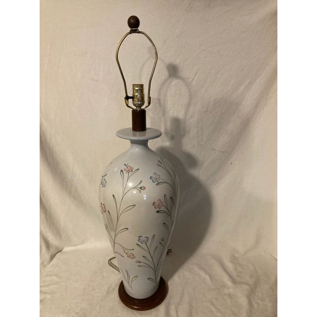 Tall light baby blue ceramic table lamp with hand painted dainty pink and blue flowers on long graceful stems. Sits on a...