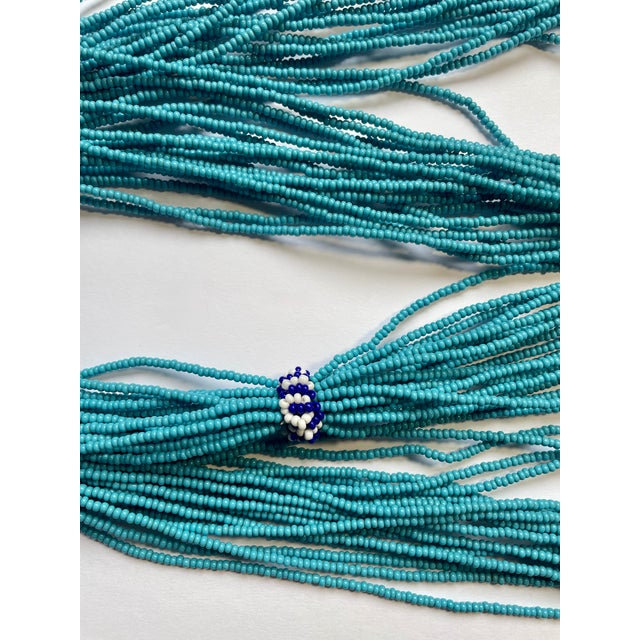Bought in South Africa in the early 2000s. This is an 18-strand “seed”- sized glass-beaded necklace. Primarily turquoise-...