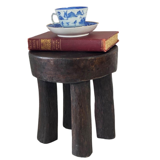 Expertly carved from a single piece of wood, this vintage African Old Carved Wood Milk Stool showcases four sturdy legs...