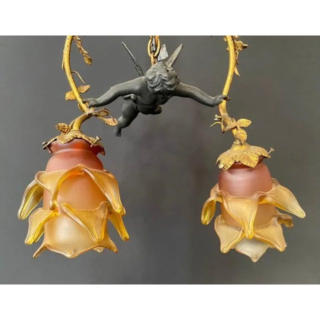 A marvelous French art nouveau flying putto cherub chandelier or pendant. The two light chandelier features a putto...