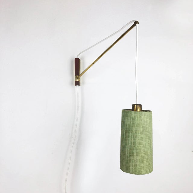 This wall light was designed and produced in Denmark in the 1960s. The wall fixture is made of metal with a brass-toned...