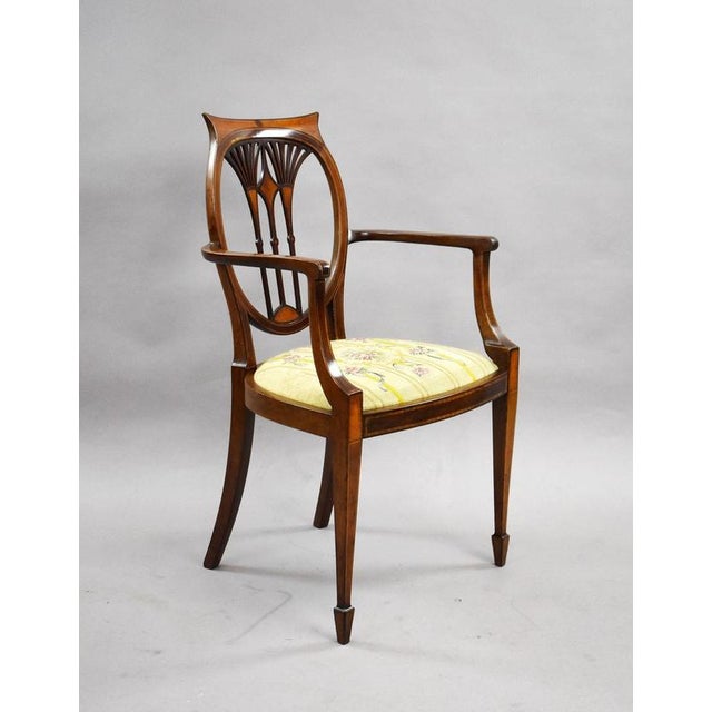 An elegant pair of Edwardian Sheraton Revival mahogany armchairs, displaying refined neoclassical detailing throughout....
