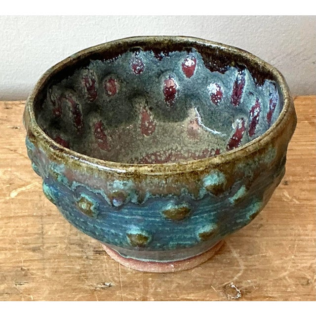 This mesmerizing studio pottery bowl is defined by its deep, rich coloration and unique textural elements. The piece...