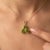 A vibrant three-stone design featuring round-cut natural peridots arranged in a graceful trefoil formation, secured in a...