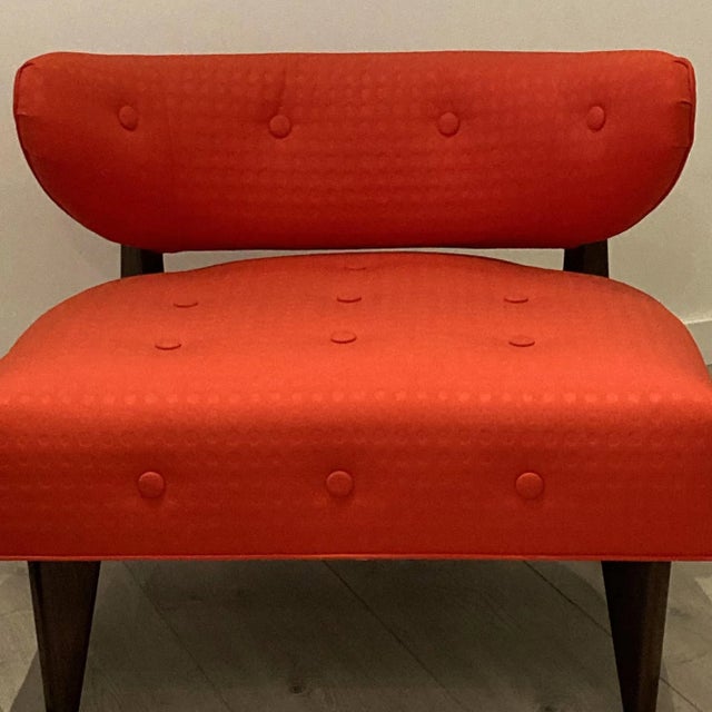 This modern Hug Chair, with wood frame, Black & Brown mahogany finish is upholstered in orange-red fabric, cushioned seat,...